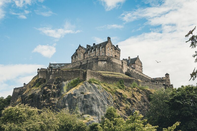 Edinburgh Castle - View of Edinburgh Castle with blue skies and wispy clouds (© Photo by Jörg Angeli on Unsplash)