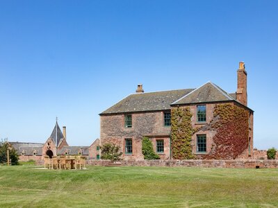 The Farmhouse new addition to The Edinburgh Address - Traditional brick farmhouse on open land with a blue sky.