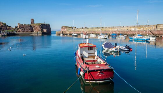 Let your worries drift away at Dunbar Harbour - A red fishing boat in a harbour with the blue sky reflected in the water. (© Amelia Whittaker @ Visit Scotland) Let your worries drift away at Dunbar Harbour - A red fishing boat in a harbour with the blue sky reflected in the water. (© Amelia Whittaker @ Visit Scotland)