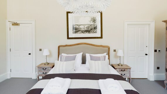 Bedroom in a Family Friendly Apartment - Master bedroom featuring an en-suite bathroom and a soothing beige palette with elegant wooden accents (© The Edinburgh Address)