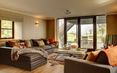 Bright Living Room Area in Scotland - Cosy lounge featuring a large dark-coloured sofa, an elegant table and stunning views