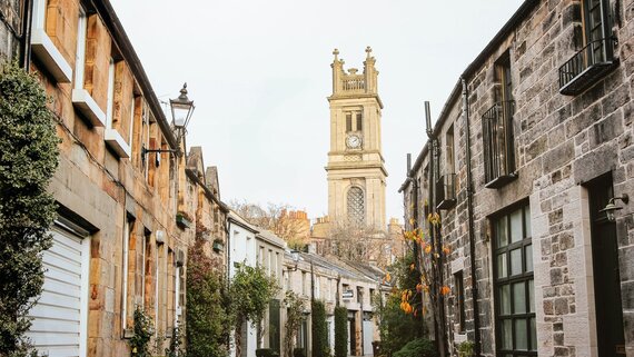 Circus Lane in Edinburgh in 2024 - A quiet traditional lane in Edinburgh, with houses lining either side of the roads, and a clock tower in the centre of the image.
