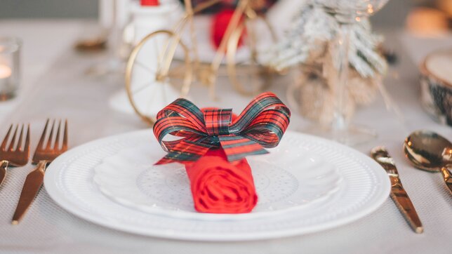 Enjoy an Edinburgh Christmas Afternoon Tea, lunch and dinner - Christmas table setting with a red napkin and tartan bow. (© Libby Penner on Unsplash)