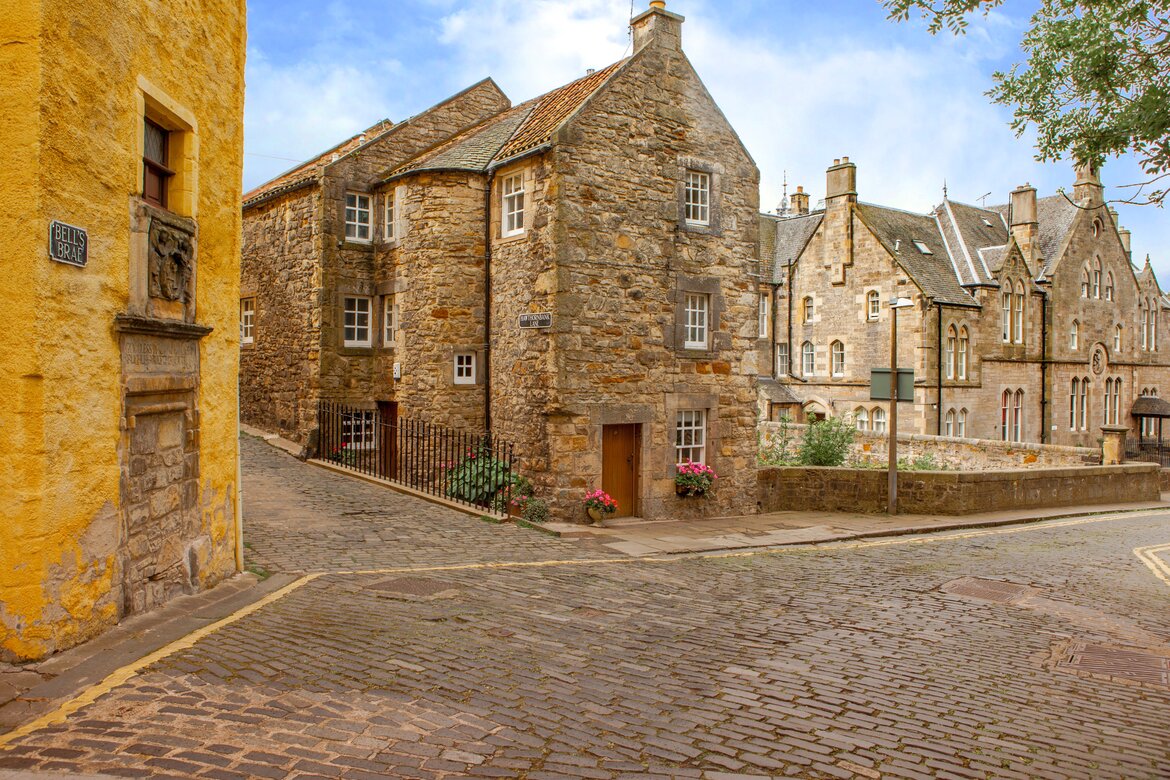 Visit the historical Dean Village in Edinburgh - Historical stone buildings line a cobbled road.