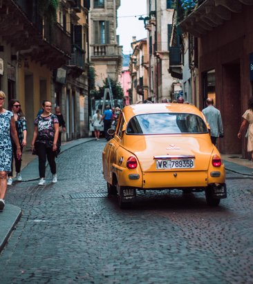 yellow-sedan-on-road-while-people-walking-on-sidewalk-1498843