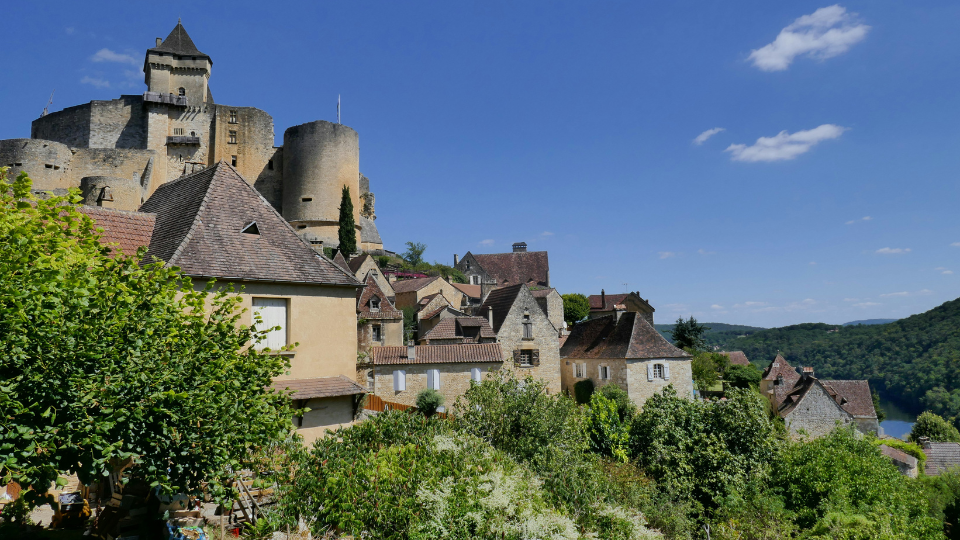 Visit Castelnaud La Chapelle in Castelnaud-la-Chapelle, France - A castle on a hill with blue skies. (© Voyage d'Alex on Unsplash)