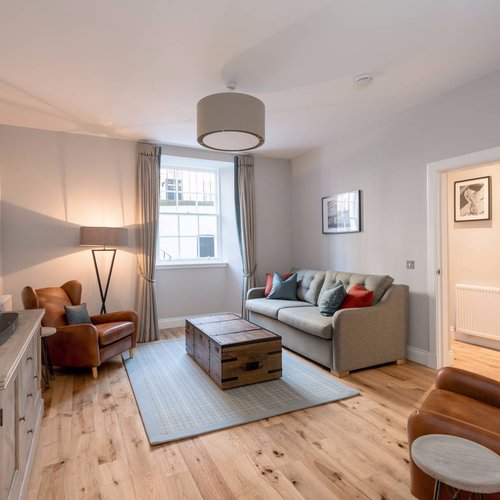 Spacious lounge with grey and brown colour scheme in Edinburgh West End apartment.
