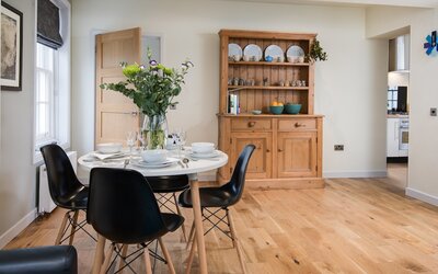 Dining Room in a Holiday Home - Elegant and spacious dining room with a wooden floor, modern table, comfy chairs and ambient lighting Dining Room in a Holiday Home - Elegant and spacious dining room with a wooden floor, modern table, comfy chairs and ambient lighting