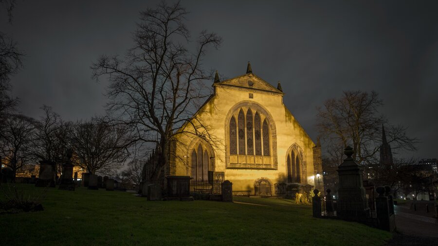 Greyfriar's Kirk, Edinburgh - A lit up building with stained glass windows with bare trees on either side, at night. (© Visit Scotland) Greyfriar's Kirk, Edinburgh - A lit up building with stained glass windows with bare trees on either side, at night. (© Visit Scotland)