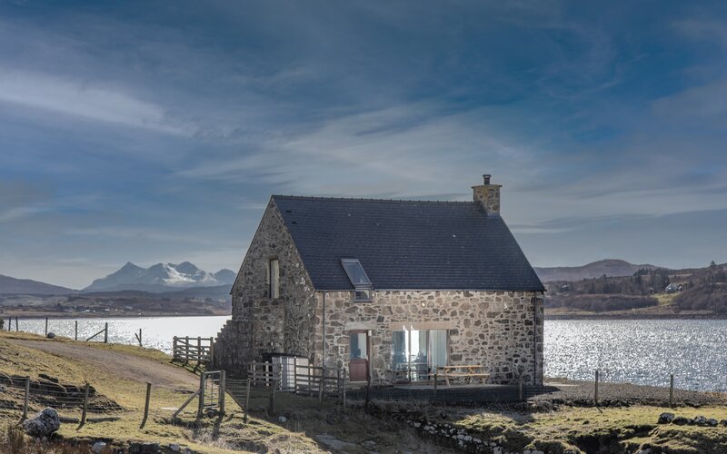 Exterior View of a Holiday Let in  Scotland - A stunning stone cottage featuring outdoor seating, with dramatic mountain and loch views