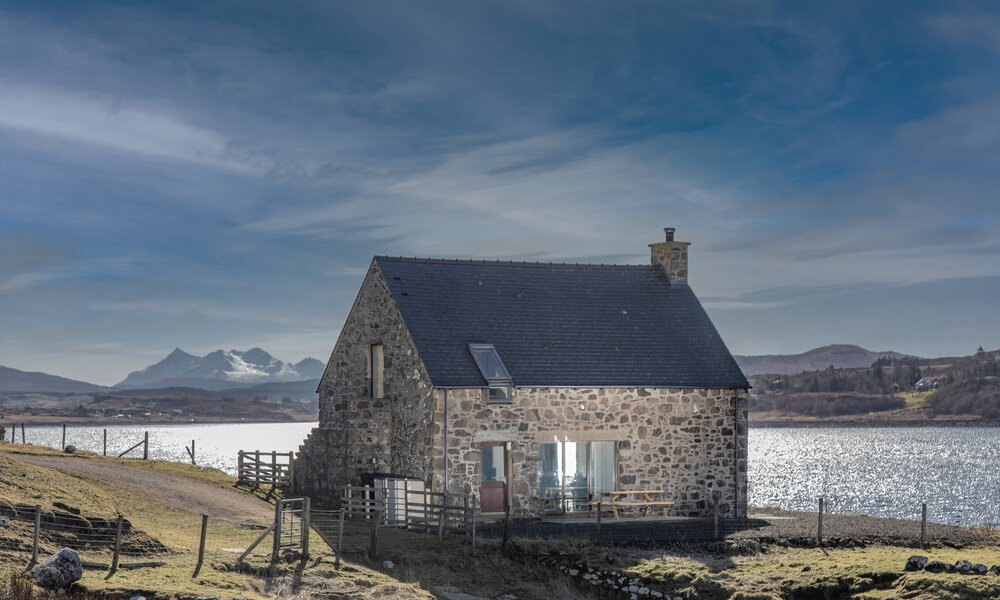 Exterior View of a Holiday Let in  Scotland - A stunning stone cottage featuring outdoor seating, with dramatic mountain and loch views