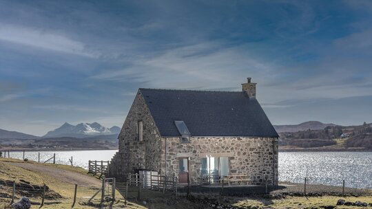 Exterior View of a Holiday Let in  Scotland - A stunning stone cottage featuring outdoor seating, with dramatic mountain and loch views
