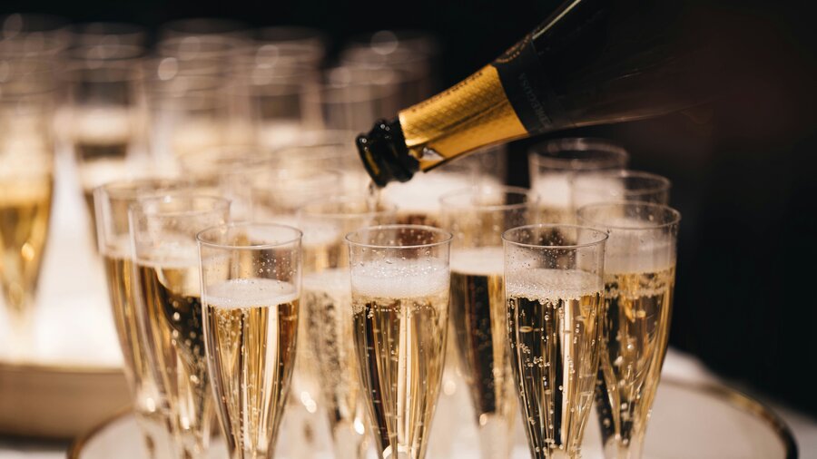 Toast in the New Year of 2025 in East Lothian - A tray of glasses is filled from a bottle of champagne. (© Alexander Naglestad)
