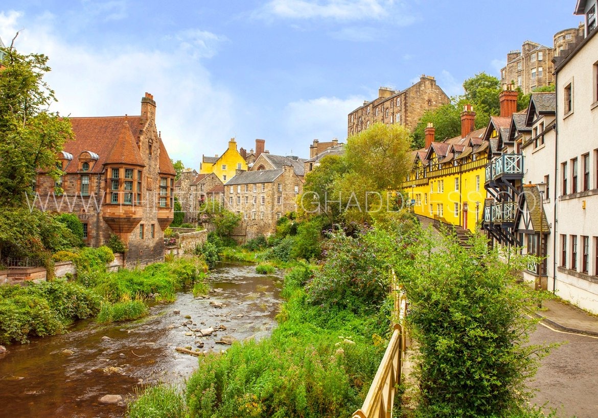 Dean Village in Edinburgh - A river running between colourful homes, with a blue sky.