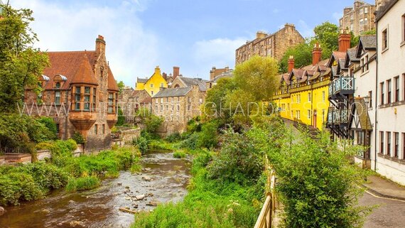 Dean Village in Edinburgh - A river running between colourful homes, with a blue sky.