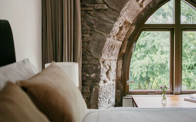 Bedroom in a Self-Catered House - A bed next to a big arched window with stunning views.