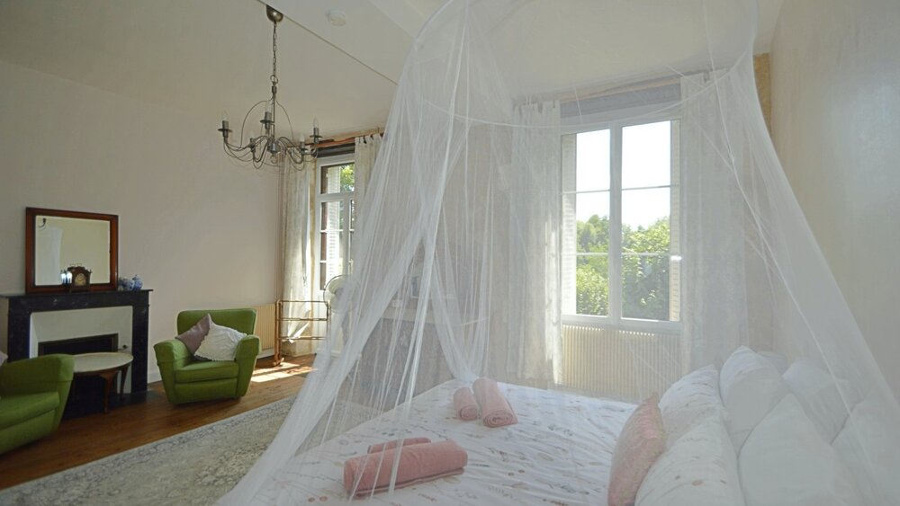Master bedroom - Bright light bedroom with double bed and mosquito net canopy. White and pink bed linen, french style doors, sunbathed room. Wooden floorboards (© Voila Villas France)