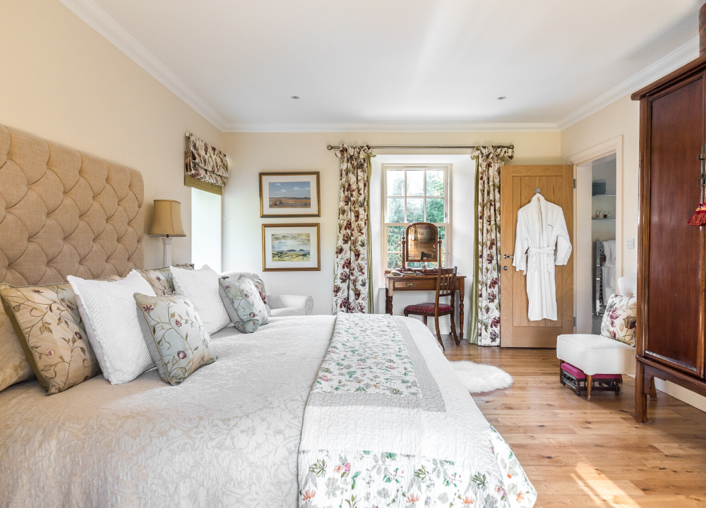 Double bedroom of The Riverside House - A large white bedroom with wooden flooring and super kingsize bed in the foreground.