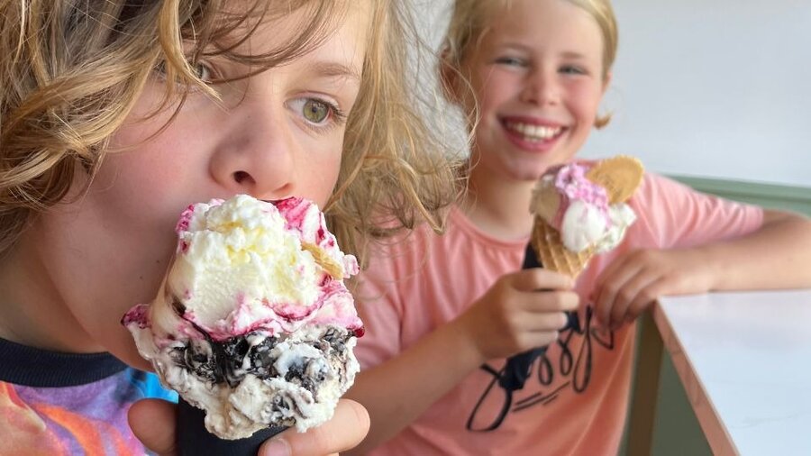 Enjoy the best ice-cream in East Lothian - A boy in the foreground eating ice-cream on a cone and a girl in the background smiling and holding her ice-cream. Enjoy the best ice-cream in East Lothian - A boy in the foreground eating ice-cream on a cone and a girl in the background smiling and holding her ice-cream.