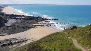 CS Holiday Lets Beach - Golden sands and a blue sea with a grassy area in the foreground.