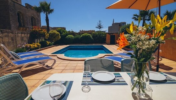 4-bedroom holiday villa in Gozo with private pool and outdoor dining terrace - An outdoor scene with a table set for a meal in front of an outdoor pool. (© Dar Ta Censina)