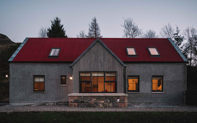 Perfect traditional west highland home sitting in a beautiful natural landscape - A view of the cottage from outside as the sun sets across the lake
