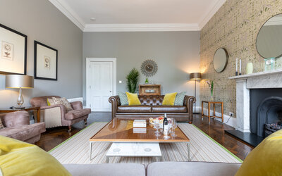 Lounge in a Holiday Rental in Edinburgh - Spacious living room featuring sumptuous seating, a large table, a fireplace and chic décor