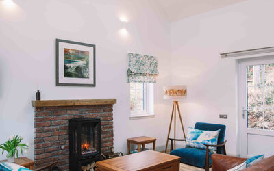Part of the sitting room; leather couch with velvet armchairs - A spacious, bright and airy sitting room with a cathedral ceiling, skylights and comfortable furniture.  The fireplace was built by the owner using reclaimed Victorian brick and an oak beam.