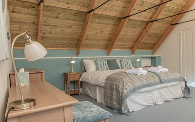 Tranquil Bedroom for a Rural Break on the Isle of Skye - Spacious bedroom with elegant vaulted timber ceilings and soft teal accents, creating a calm and inviting space for a rural retreat
