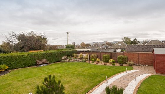 Scottish holiday homes with private gardens - A holiday home garden with grassy zone and pathway. (© The Traquair Park Residence)