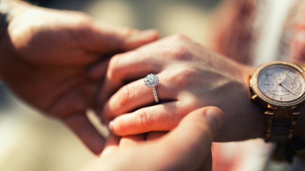 Propose to your loved one in East Lothian - A man and a woman holding hands with an engagement ring on her left ring finger. (© James Lewis on Unsplash)