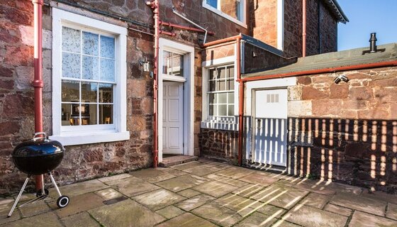 Holiday home in Scotland with a private courtyard - A fenced stone courtyard with black round barbecue. (© Firth View Apartment)