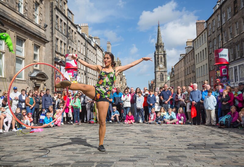 Edinburgh Fringe Festival street performer - Street performer with hulahoop on cobbled street surrounded by people (© VisitScotland / Kenny Lam) Edinburgh Fringe Festival street performer - Street performer with hulahoop on cobbled street surrounded by people (© VisitScotland / Kenny Lam)