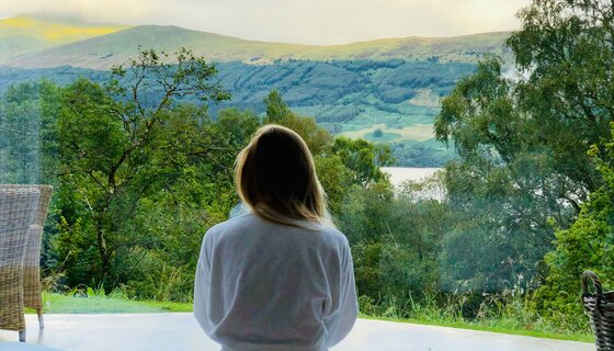 Tranquil holiday stays in Scotland - A view over a womans shoulder as she looks at the green hills of Scotland. (© Sam Carter)