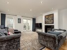 Living Room - Spacious open plan living area of Edinburgh holiday home, featuring patio doors, fireplace and large TV .