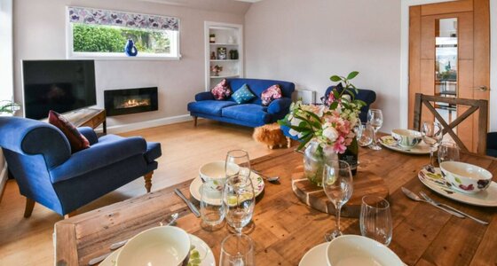 Spacious Living & Dining Room with Serene Garden Views - A bright, inviting living room featuring a comfortable seating area, a wooden dining table, an electric fireplace and delightful garden views