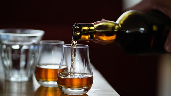 Scotch Whisky Experience in Edinburgh - Golden whisky pouring from a bottle into two glasses alongside a glass of water.