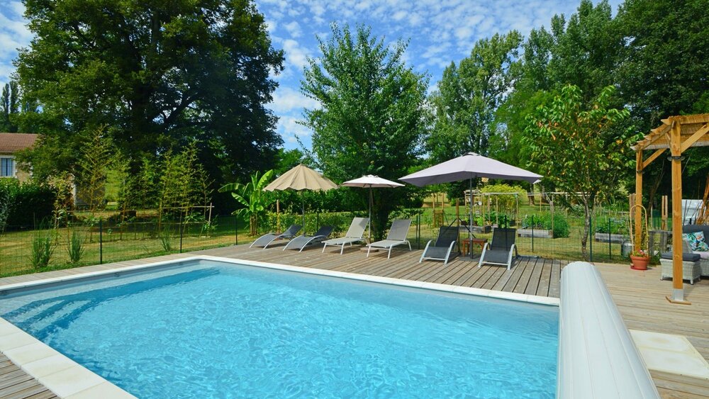 Private Swimming Pool - Blue swimming pool, with parasols and sun loungers, decking and pool cover. Tree lined private garden (© Voila Villas France)