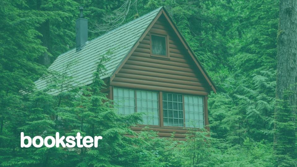 Lodges and Holiday Homes - A brown lodge nestled in a forest with a Bookster logo. (© Thomas Le @ Unsplash)