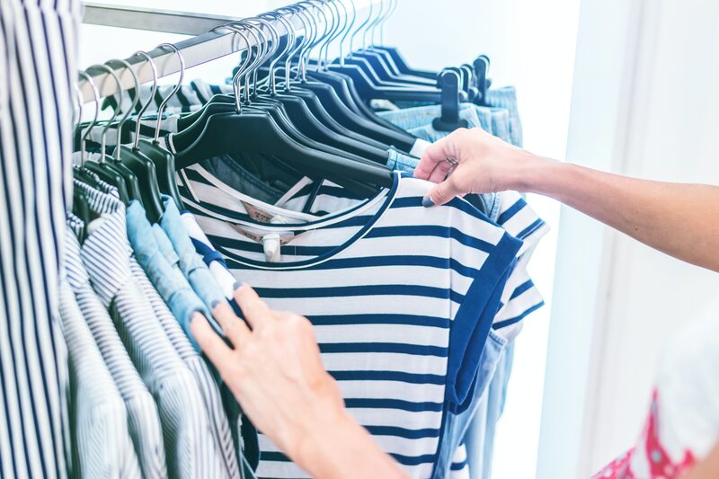 Enjoy Edinburgh's shopping experience - Searching through a clothes rack (© Artem Beliaikin on Unsplash)