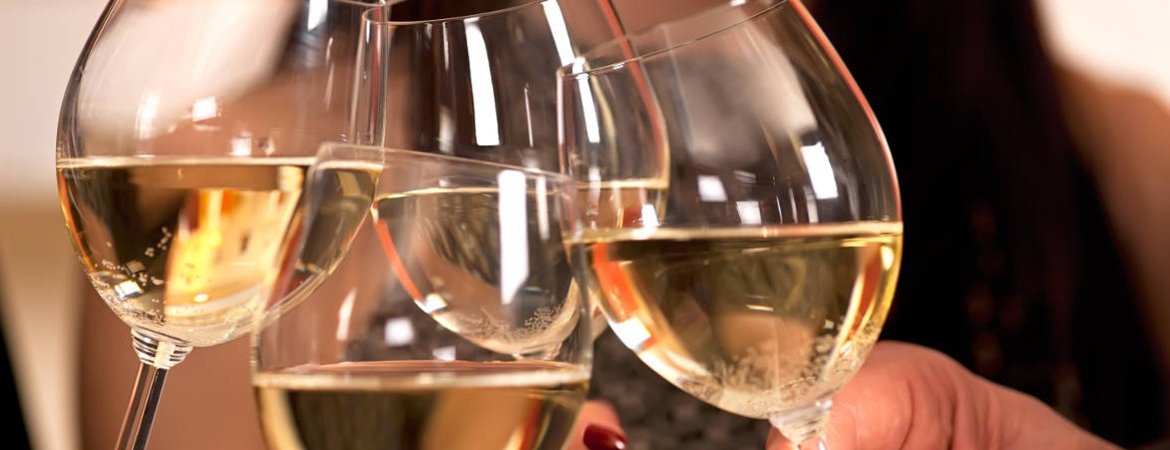 A toast with four glasses of white wine