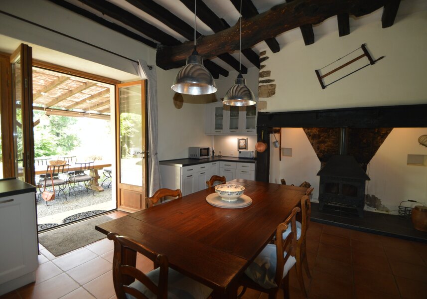 Cuisine coin repas, table et cheminée ouverte sur le jardin