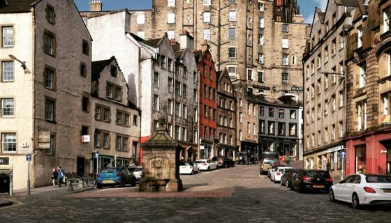 Homes with free outdoor parking - A city lined with cars with tall stone buildings. (© Jingtao @ Unsplash)