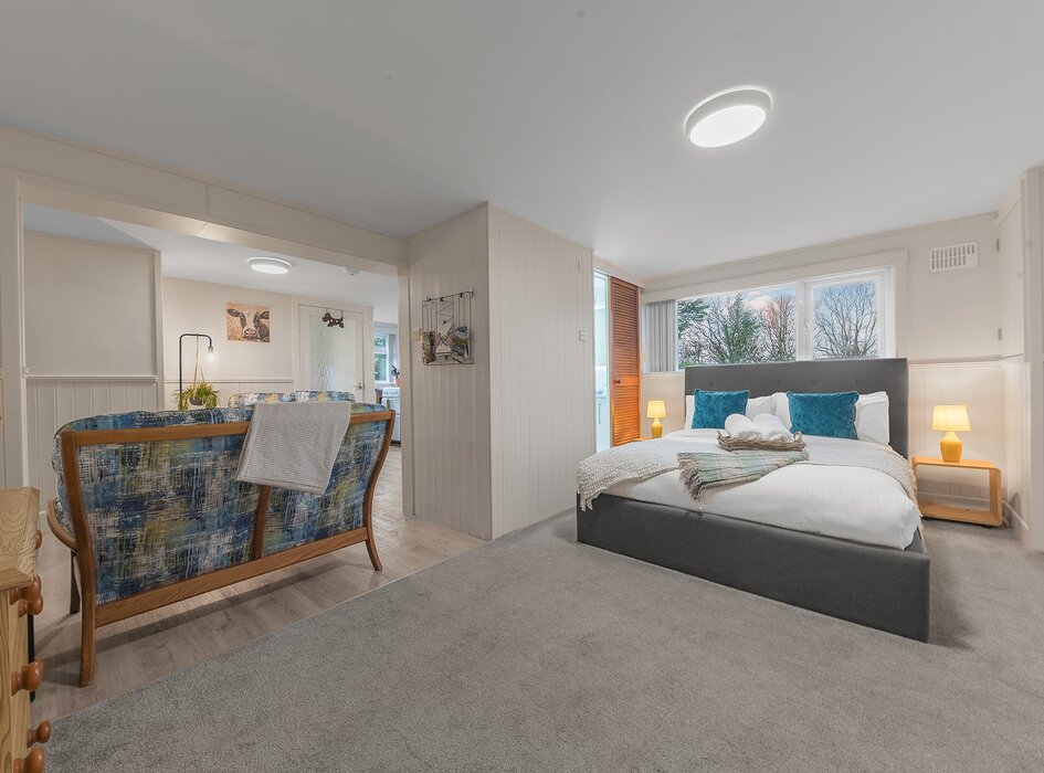 Open plan space for studio near Bowness - Comfortable double bed with white linen, hanging rail, chest of drawers with en suite shower room leading into open plan lounge, kitchen and breakfast bar.