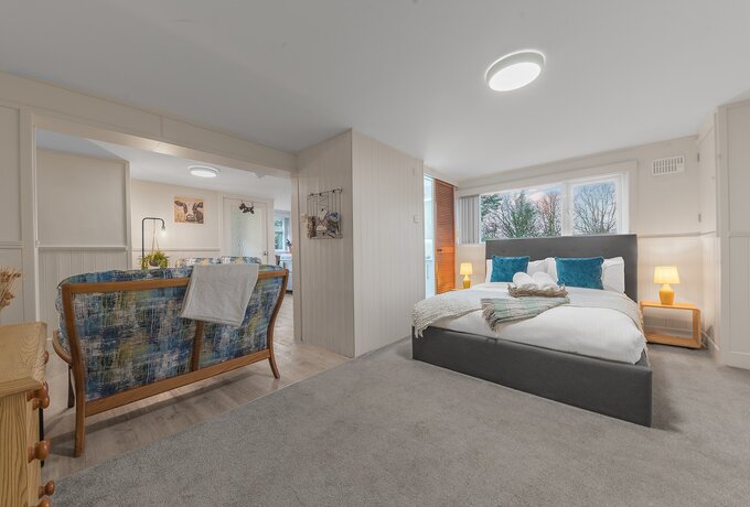 Open plan space for studio near Bowness - Comfortable double bed with white linen, hanging rail, chest of drawers with en suite shower room leading into open plan lounge, kitchen and breakfast bar.