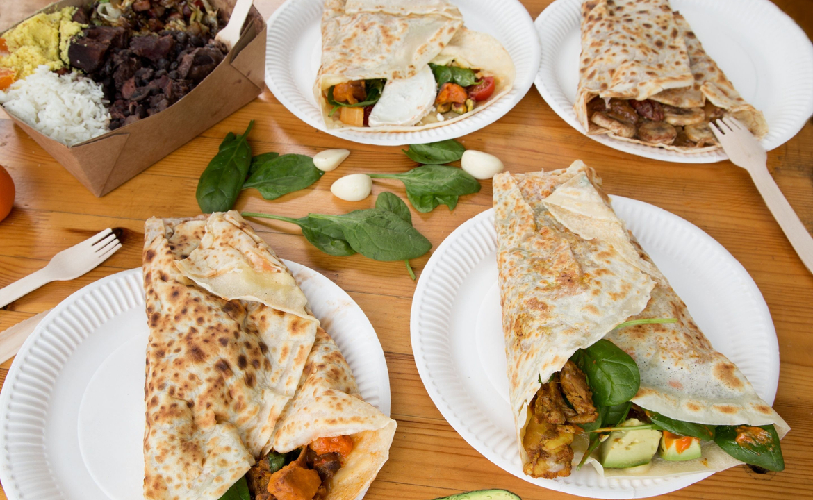 Tupiniquim crepes - A table covered in plates of filled crepes.