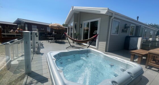 hot tub side view of lodge, garden furniture and hammock - side view of balcony, glass wrap around veranda with sunken hot tub, hammock