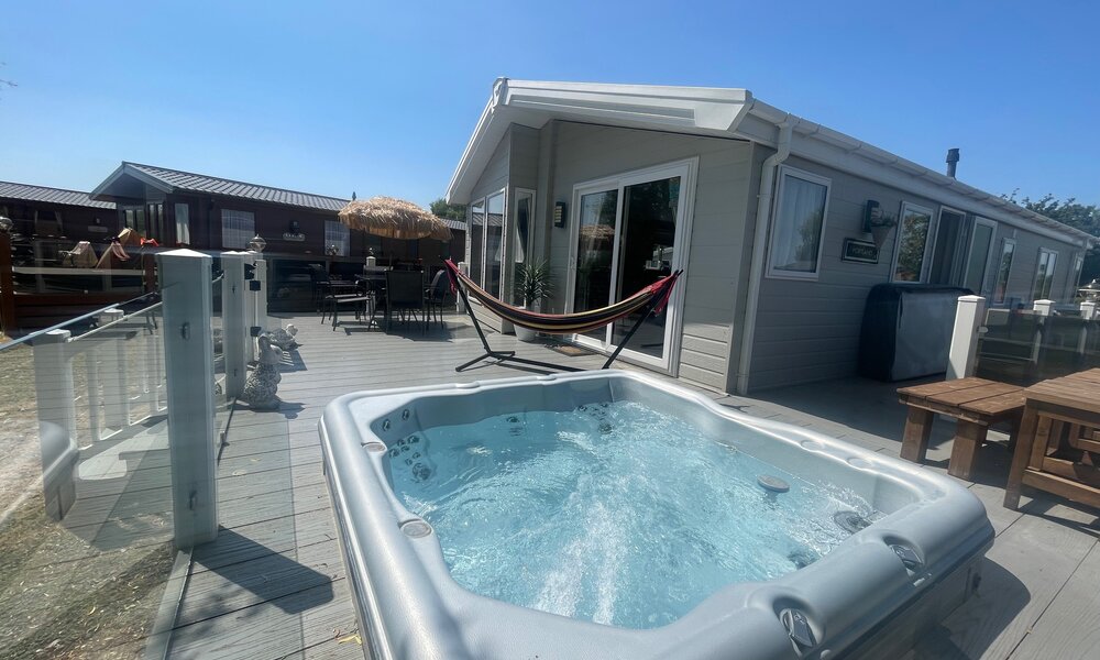 hot tub side view of lodge, garden furniture and hammock - side view of balcony, glass wrap around veranda with sunken hot tub, hammock