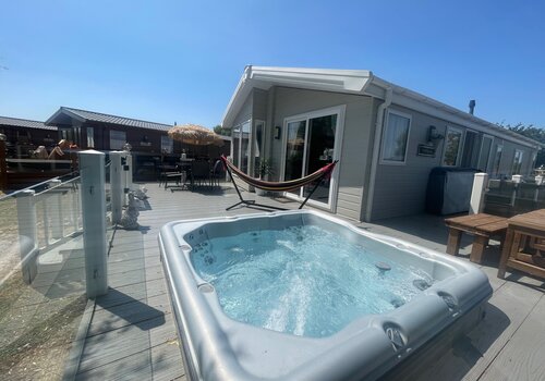 hot tub side view of lodge, garden furniture and hammock - side view of balcony, glass wrap around veranda with sunken hot tub, hammock