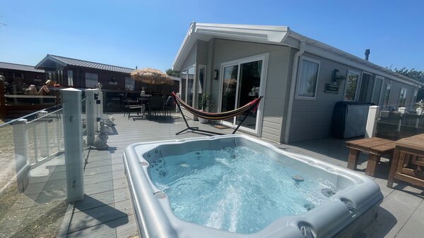 hot tub side view of lodge, garden furniture and hammock - side view of balcony, glass wrap around veranda with sunken hot tub, hammock